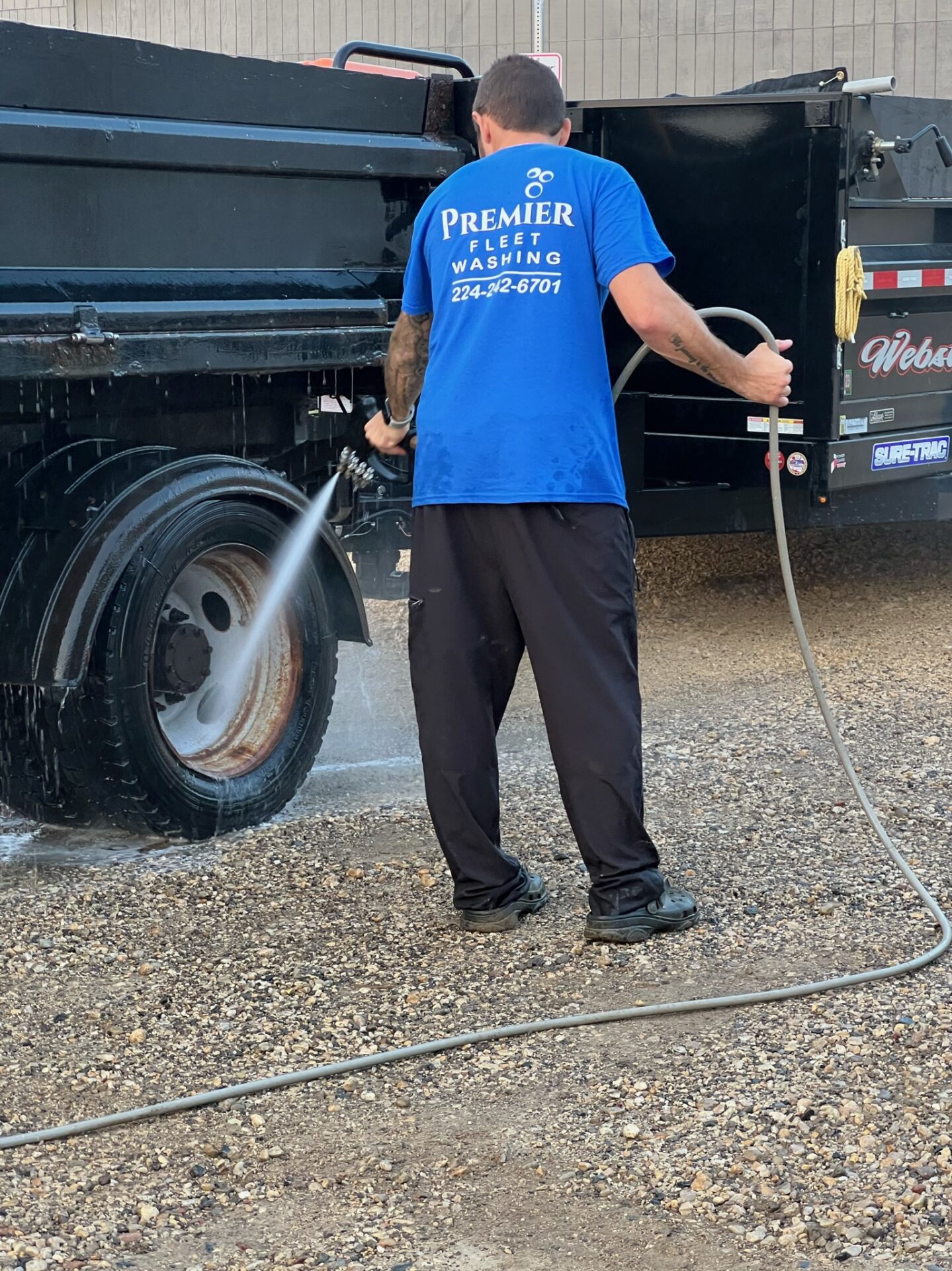 A man is washing the truck with a hose.