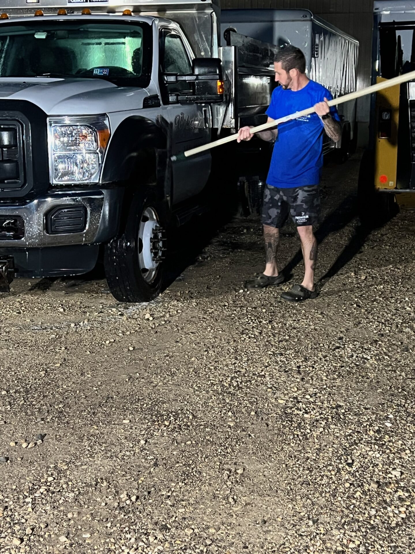 A man holding a pole in front of a truck.