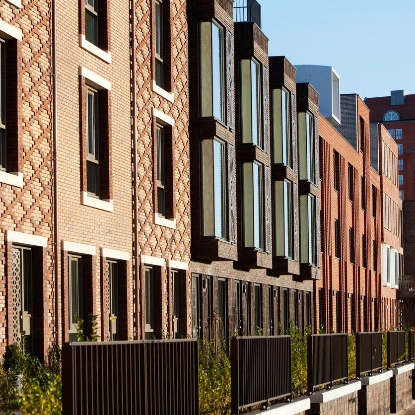 A row of brick buildings with windows and balconies.